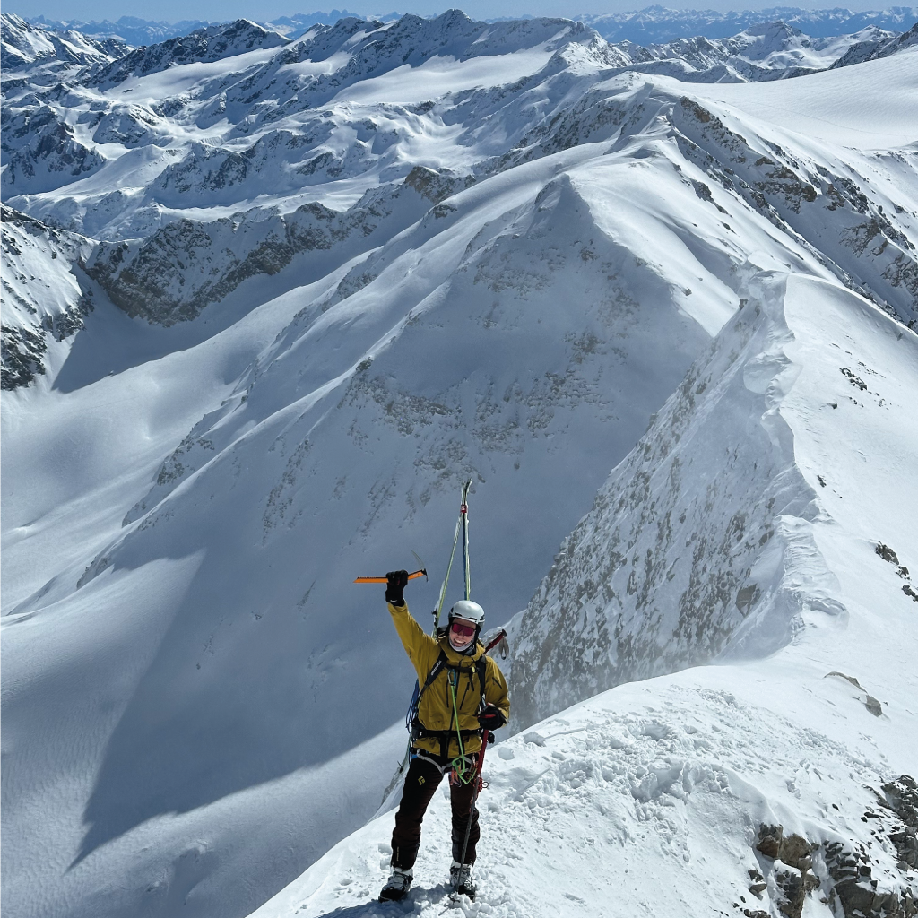 Rémi en montagne sur une arête neigeuse avec un arrière-plan de haute montagne.