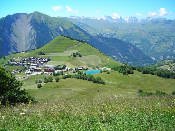 Photographie du village d'Albiez-Montrond en été avec des montagnes enneigées en arrière plan.