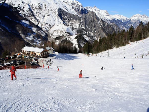 Photographie de la station de ski alpin du col d'Ornon avec une piste, des skieurs et un paysage enneigé.