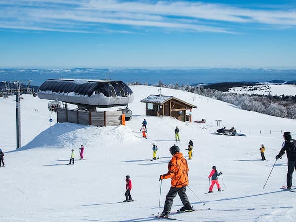 Remontée mécanique de la station de Chalmazel avec skieurs et paysages enneigés.