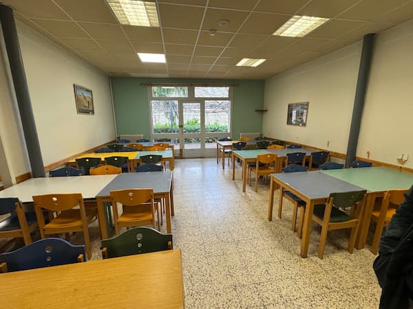 Photographie d'une salle collective avec tables et chaises.