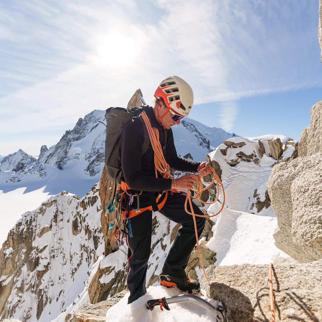 Mael sur une arête avec paysage enneigé de haute montagne en arrière plan.