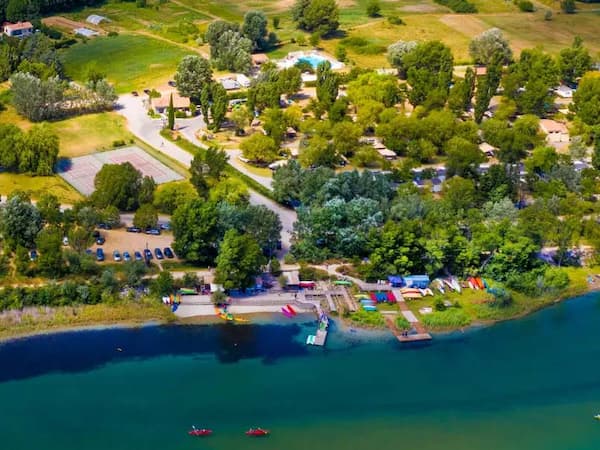 Vue aérienne du camping de Quinson au bord de la rivière avec de la verdure.